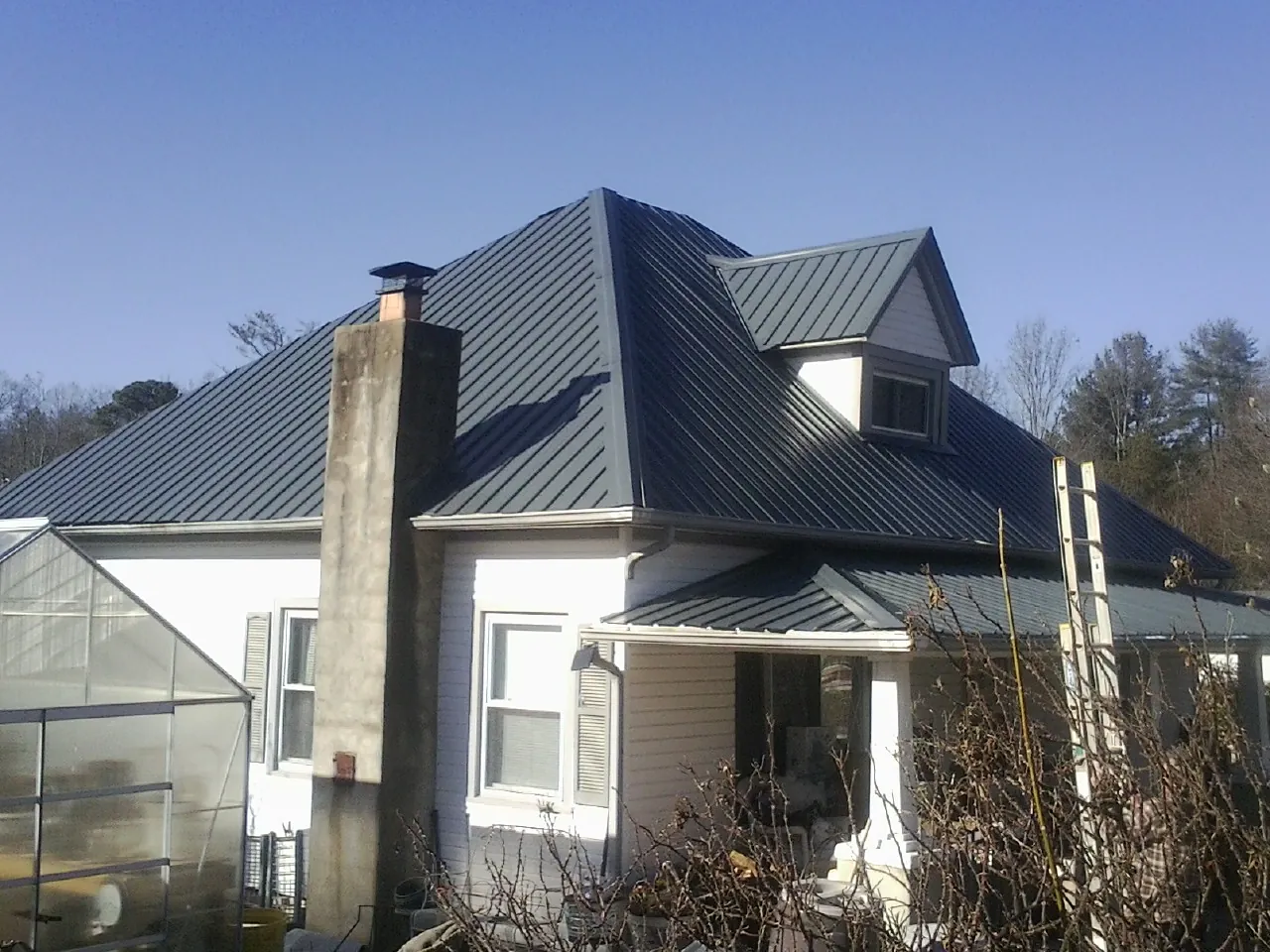 Dark blue standing seam metal roof on a white farmhouse with dormer — Slate & Tile Roof Repair by Roofing Brothers in Reno