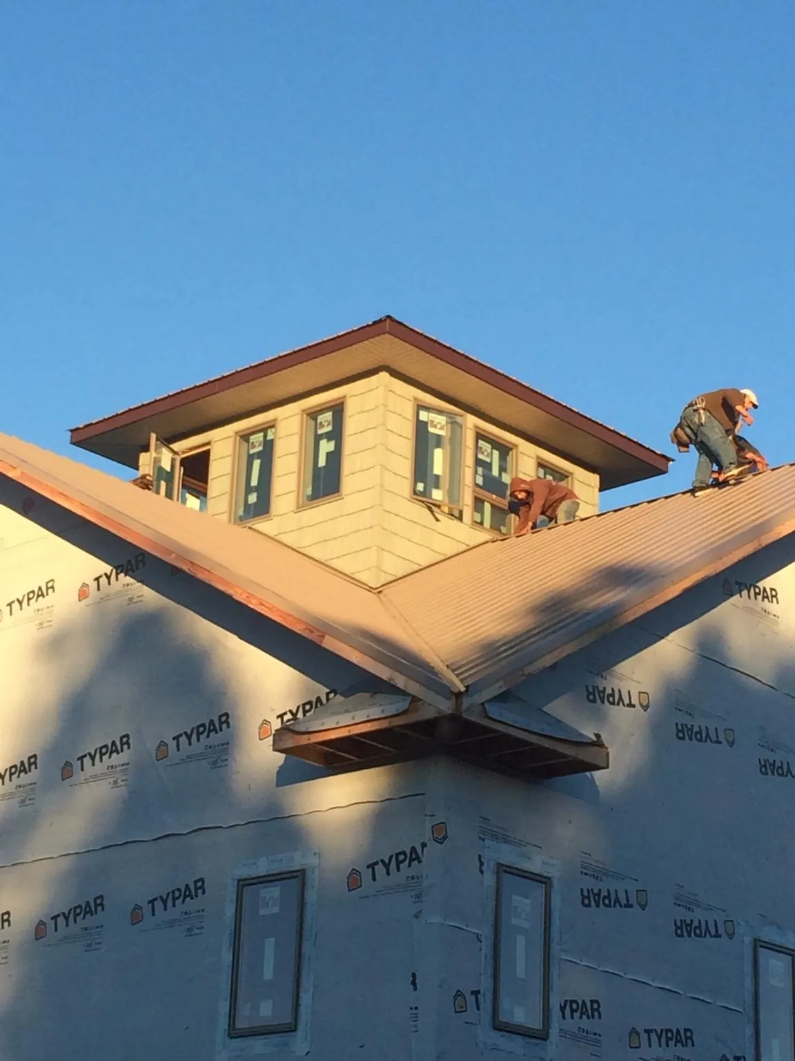 Roofers working around a rooftop cupola on a new metal roof at sunset — Roof Waterproofing in Reno by Roofing Brothers